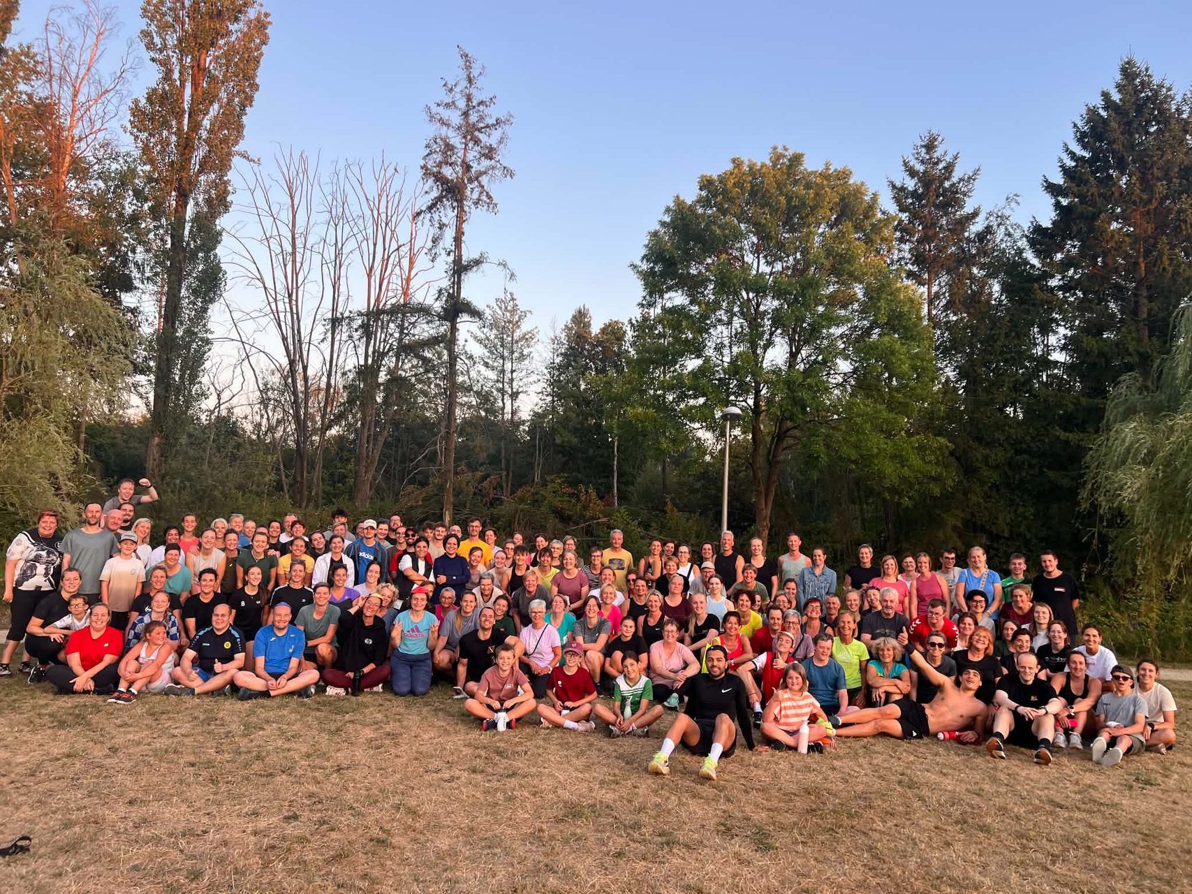 Grote groep deelnemers van de bootcamp groepsles van Activate Performance poseert buiten na de training in Mol